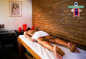 Hóspede deitada na maca de massagem em sala iluminada por velas