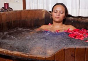Mulher relaxando em banheira de madeira com pétalas